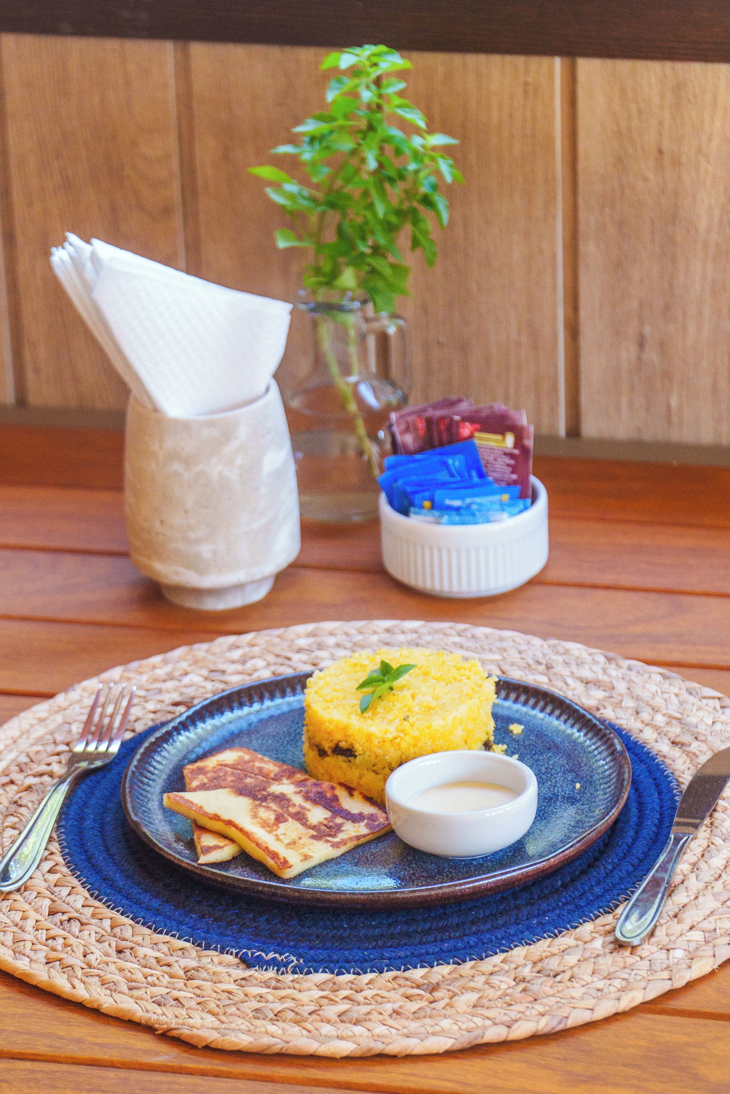 A plate with food and condiments on a woven placemat.