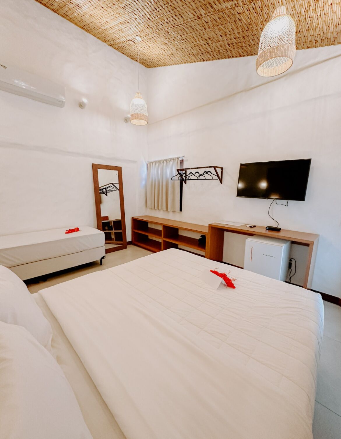 Ein modernes Hotelzimmer mit einem großen Bett, einem Fernseher, einem Schreibtisch und einem Kleiderschrank.