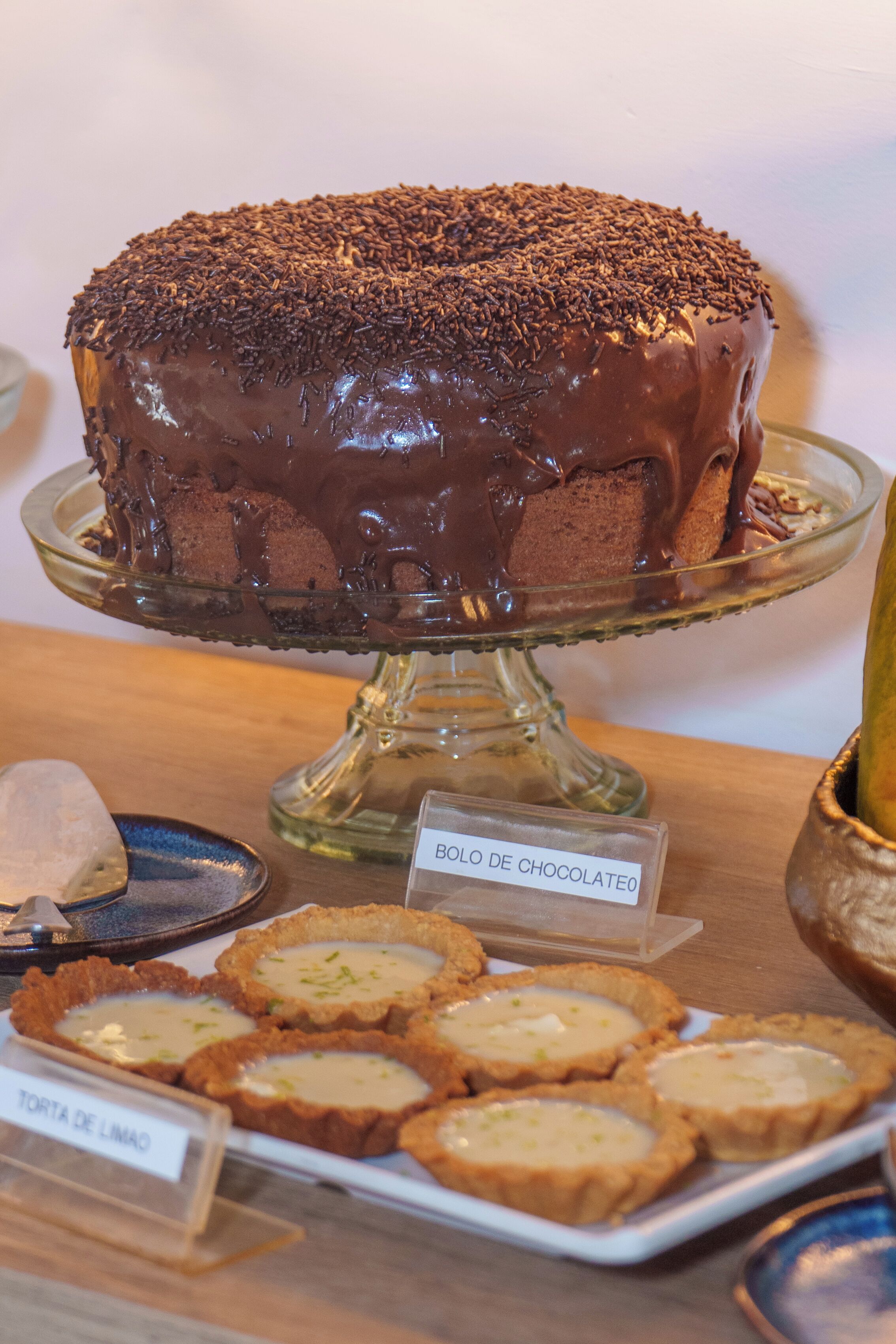 Um bolo de chocolate sobre um suporte de vidro com a etiqueta 