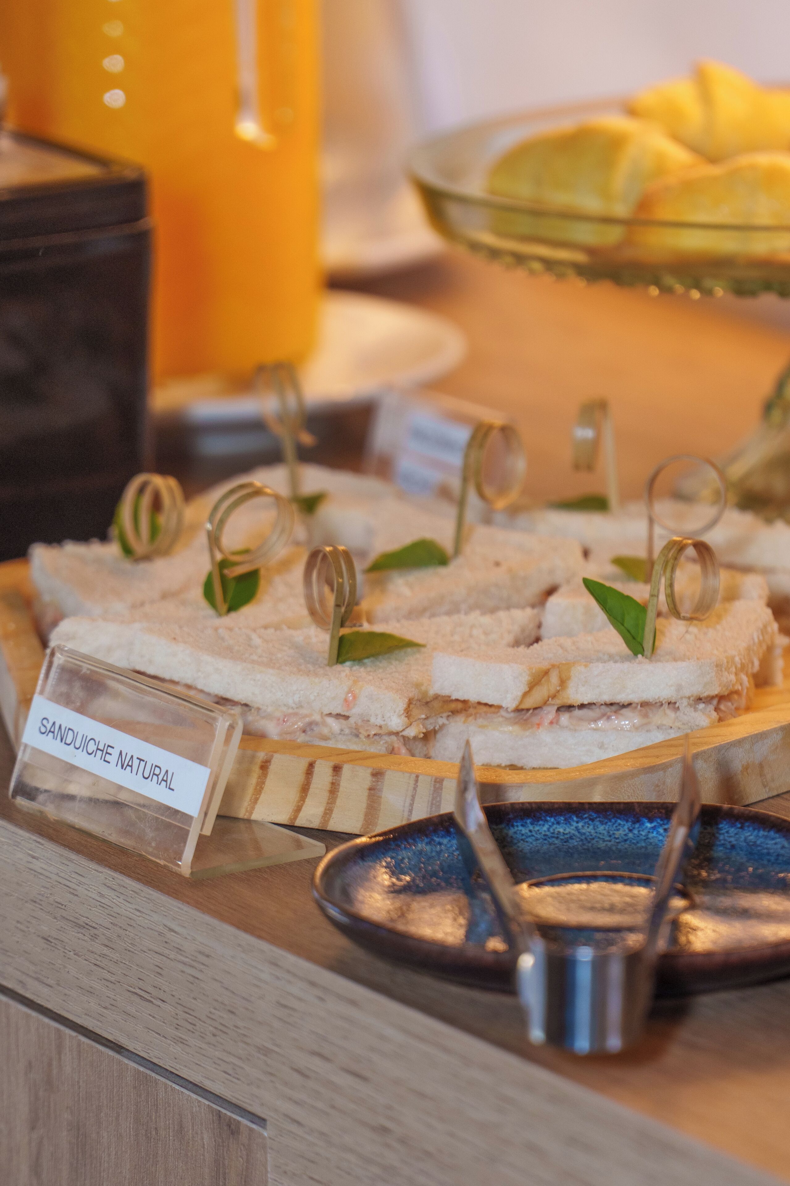 Eine Auswahl an Sandwiches mit einem Schild, auf dem "SANDUICHE NATURAL" steht, auf einem Holzboden.