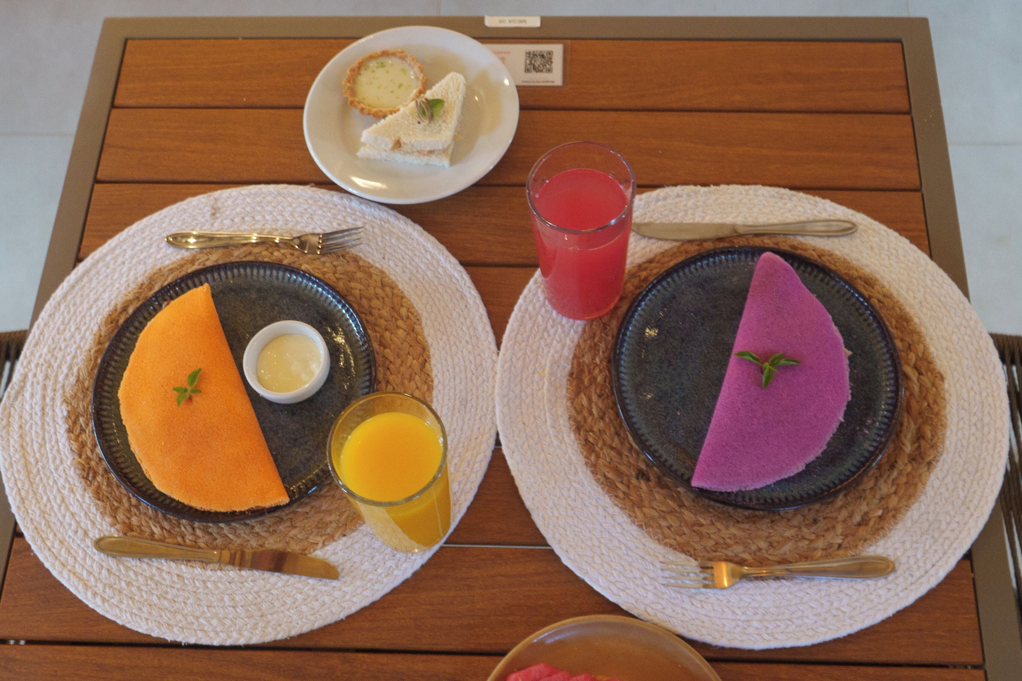 Two plates with food and drinks on a wooden table.