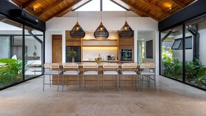 A modern kitchen with a central island, pendant lighting, and a view of the outdoors. - Villa Bahia (Cóbano)