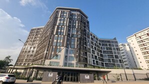 A modern multi-story building with a curved facade, large windows, and a gated entrance. - Loxwood House Apartment (Accra)