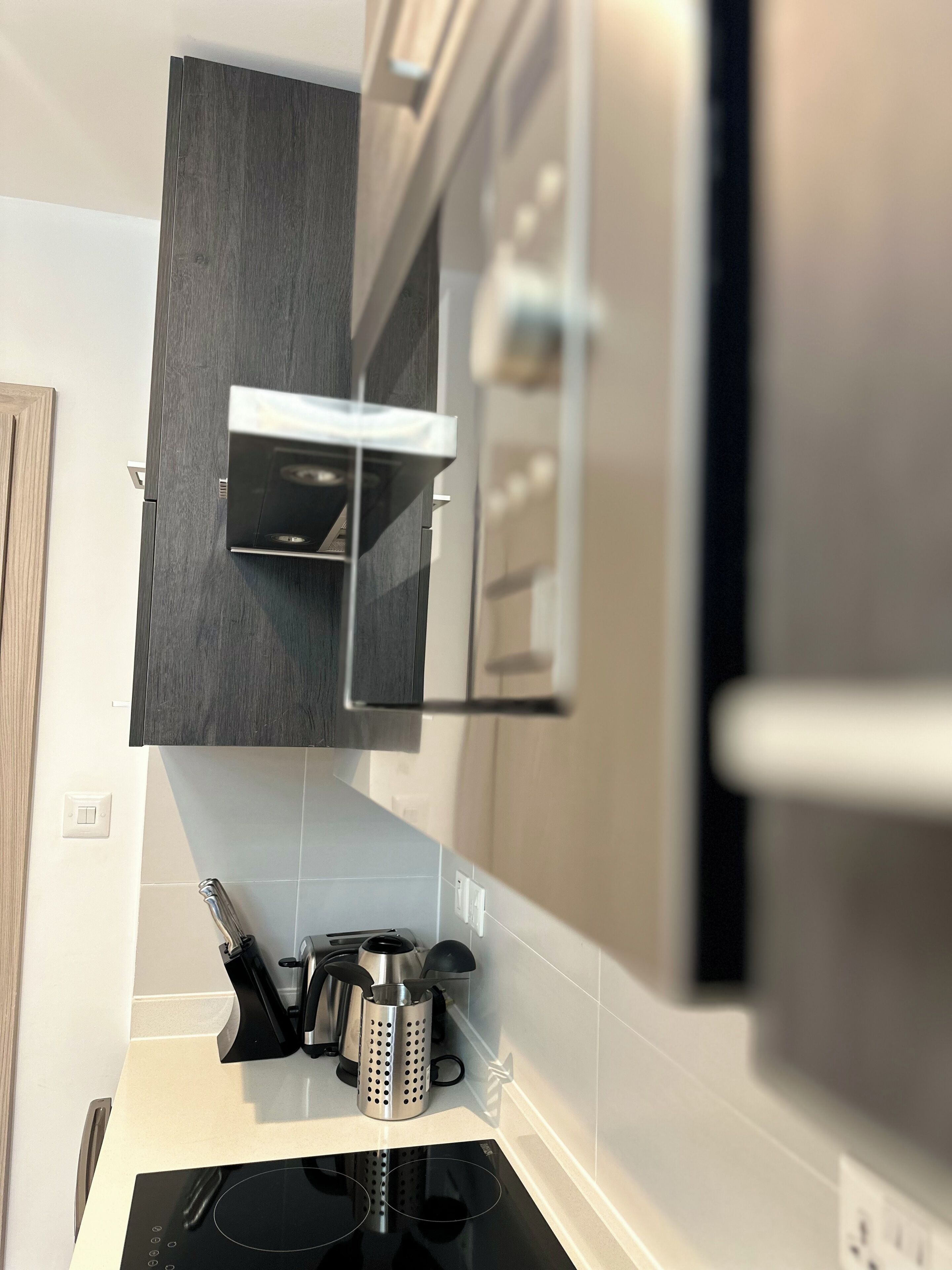 Een moderne keuken met een inbouw magnetron, een roestvrijstalen spoelbak en een waterkoker op het aanrecht.