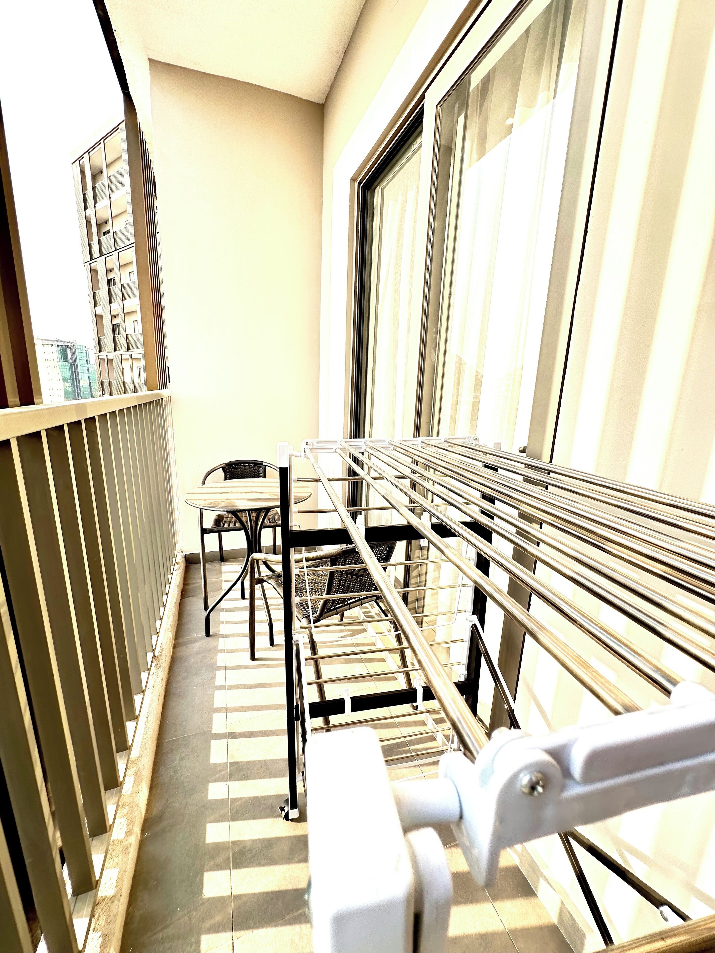 Un balcone con ringhiera in metallo, un tavolo e sedie.