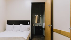 A hotel room with a bed, a wooden wardrobe, a bathroom with a mirror, and a sink. - Hospedaje Consular by Dunas (Ciudad Juárez)