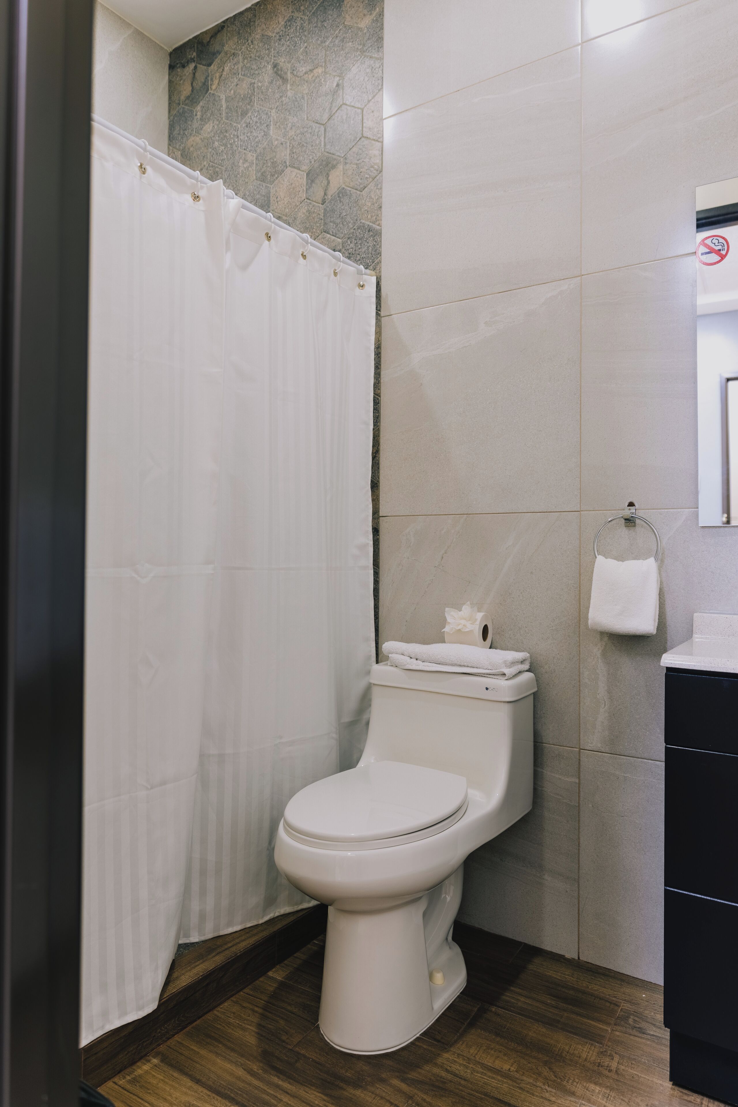 A bathroom with a toilet, a shower curtain, a towel rack, and a toilet paper holder.
