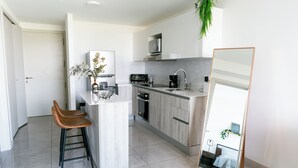 A modern kitchen with a central island, bar stools, a microwave, and a coffee maker.