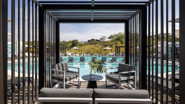 A poolside area with lounge chairs and a small table, overlooking a swimming pool.