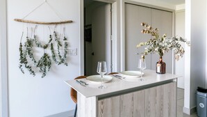 A dining area with a wooden cabinet, a hanging plant, and a vase with flowers.