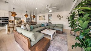 A modern living room with a sectional sofa, a coffee table, and a dining area with chairs. - Private Beach. ROCK WALL. POOL W/ Zip Line & Slide (Sarasota)