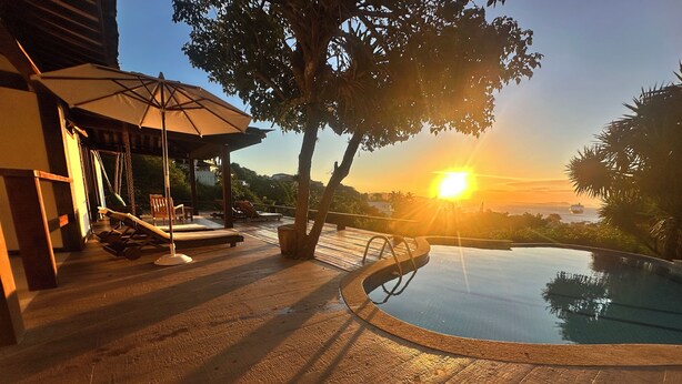 A wooden deck with a swimming pool, lounge chairs, and an umbrella. - Ilha Branca Guest House (Búzios)
