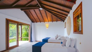 A spacious room with a high ceiling, a large bed, a second smaller bed, and a view through a sliding glass door. - Ilha Branca Guest House (Búzios)