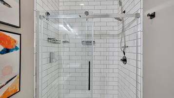A modern bathroom with white subway tiles, a glass-enclosed shower, and a black towel rack.