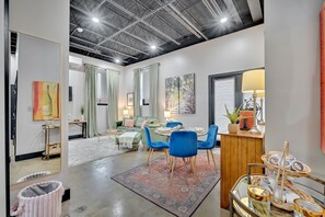 A modern living room with a dining area, featuring a high ceiling, large windows, and contemporary furniture. - The Juliette Loft: Historic Charm Meets Modern Comfort in Downtown Kingsport (Kingsport)