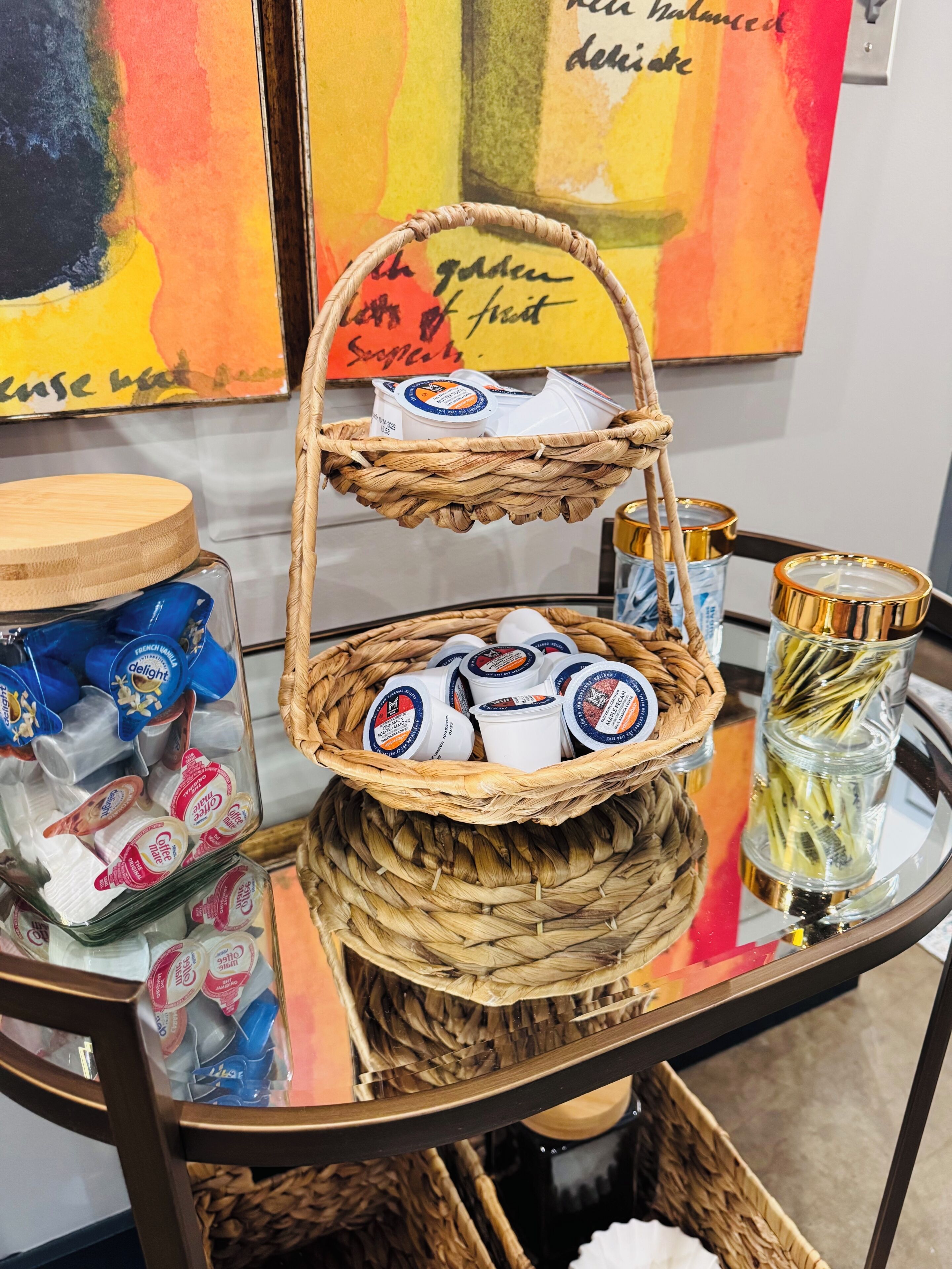 A wicker basket with containers of coffee creamer on a glass table.