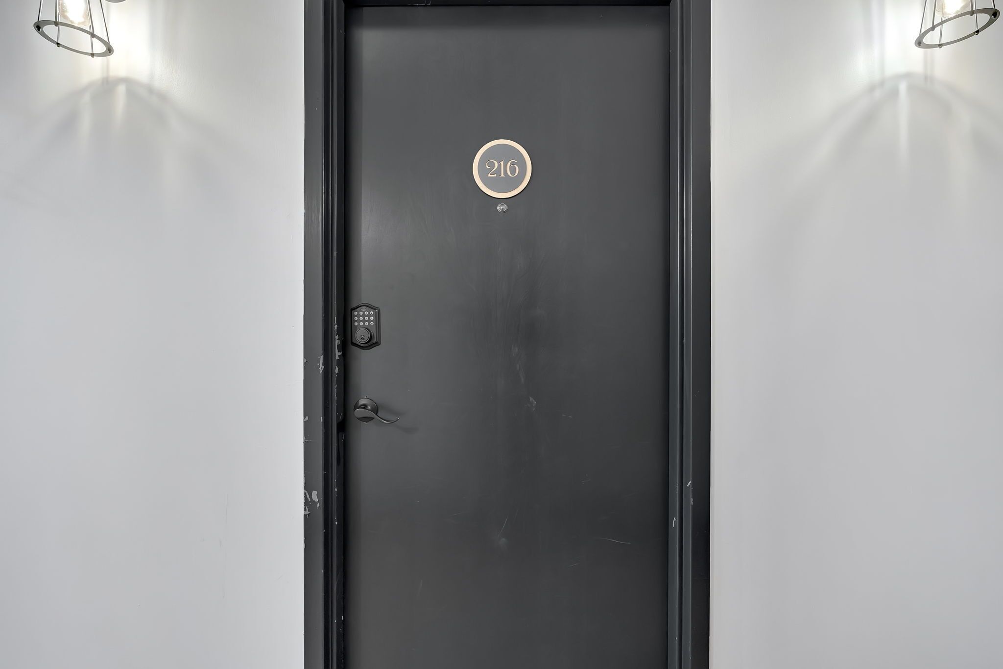 A black door with a number plate '216' and a keypad lock.
