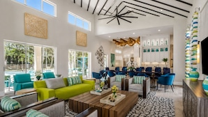 Amplia sala de estar con vista a la piscina, muebles modernos y una cocina al fondo.