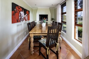 A dining room with a wooden table, dark chairs, and a large painting on the wall.