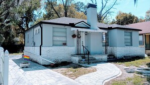 A single-story house with a white exterior, a chimney, and a front porch. - 2BR/1BA near Jax Zoo -- Welcome, Train Enthusiasts!!  (Jacksonville)