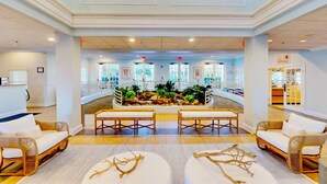 Un hall d’entrée spacieux avec un espace salon central, un élément décoratif aquatique et une vue sur la piscine.