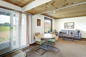 Una habitación con una mesa redonda, sillas, un sofá y una ventana con cortinas.
