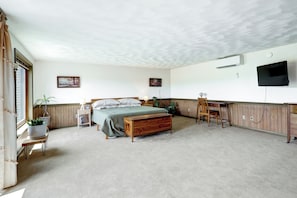 Un dormitorio con cama, mesitas de noche, un escritorio, una silla y una televisión.