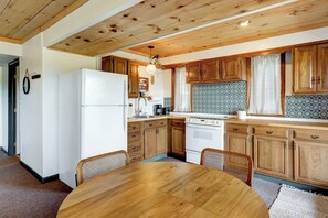 Una cocina con armarios de madera, un refrigerador blanco, una estufa y una mesa de comedor con sillas.