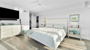 Een moderne slaapkamer met een bed, een dressoir, een nachtkastje en een televisie.