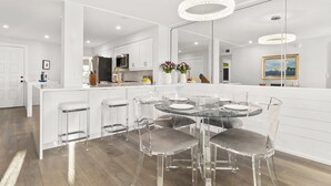 Een moderne keuken met een centraal eiland, barstoelen en een ronde eettafel met stoelen.