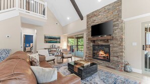 A spacious living room with a fireplace, comfortable seating, and a balcony with a view.