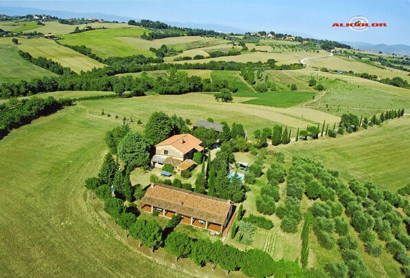 An aerial view of a rural property with a large house surrounded by vineyards and rolling hills.