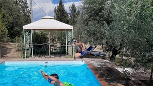 Ein Schwimmbecken mit klarem, blauem Wasser, einem Sprungbrett und einem Pavillon im Hintergrund.