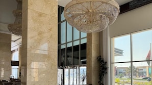 A spacious lobby with marble flooring, a large chandelier, and seating area with two sofas and chairs. - Helat hotel (Al Khobar)