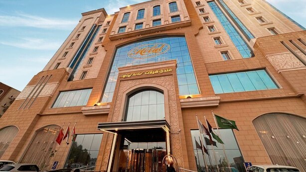 A hotel with a prominent 'Hilton' sign, multiple floors, and a large entrance with flags. - Helat hotel (Al Khobar)