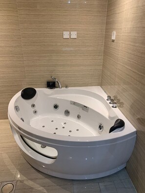A modern spa bathroom with a freestanding bathtub, a built-in bench, and a wall-mounted control panel. - Helat hotel (Al Khobar)