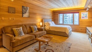 Een gezellige kamer met een houten plafond, een bed, een bank en een klein tafeltje.