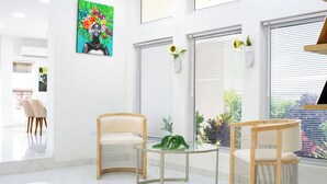 A modern interior with two wooden chairs, a glass table, and a painting on the wall. - Charming 2-bedroom villa with AC, WiFi in tranquil Osbourn-Fitches Creek  (St. Georges)