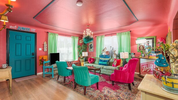 A vibrant living room with teal and pink chairs, a teal door, and a red ceiling. - Betty Blue House (Reno)