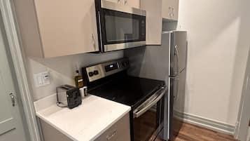 Una cocina compacta equipada con microondas, estufa y refrigerador.