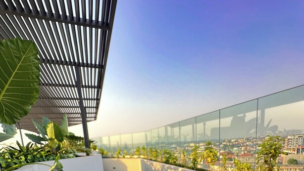 Un jardin sur le toit offrant une vue sur le paysage urbain, agrémenté d’un élément aquatique et d’une structure en forme de pergola.