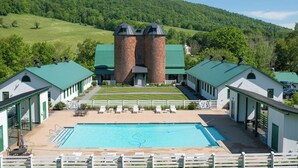 Un hotel con piscina, dos torres de ladrillo y edificios con techos verdes.