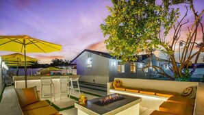 An outdoor living area with a fire pit, seating, and a bar area. - Ultimate Coachella Stay: Pool & Fun & pickleball (Coachella)