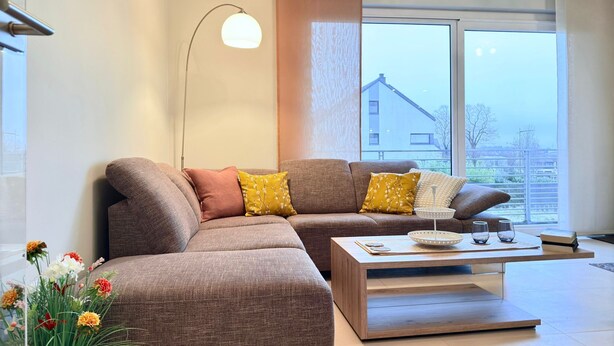 A modern living room with a sectional sofa, a coffee table, and a floor lamp. - Comfort 2 bedrooms Apt w balcony&parking (Mamer)