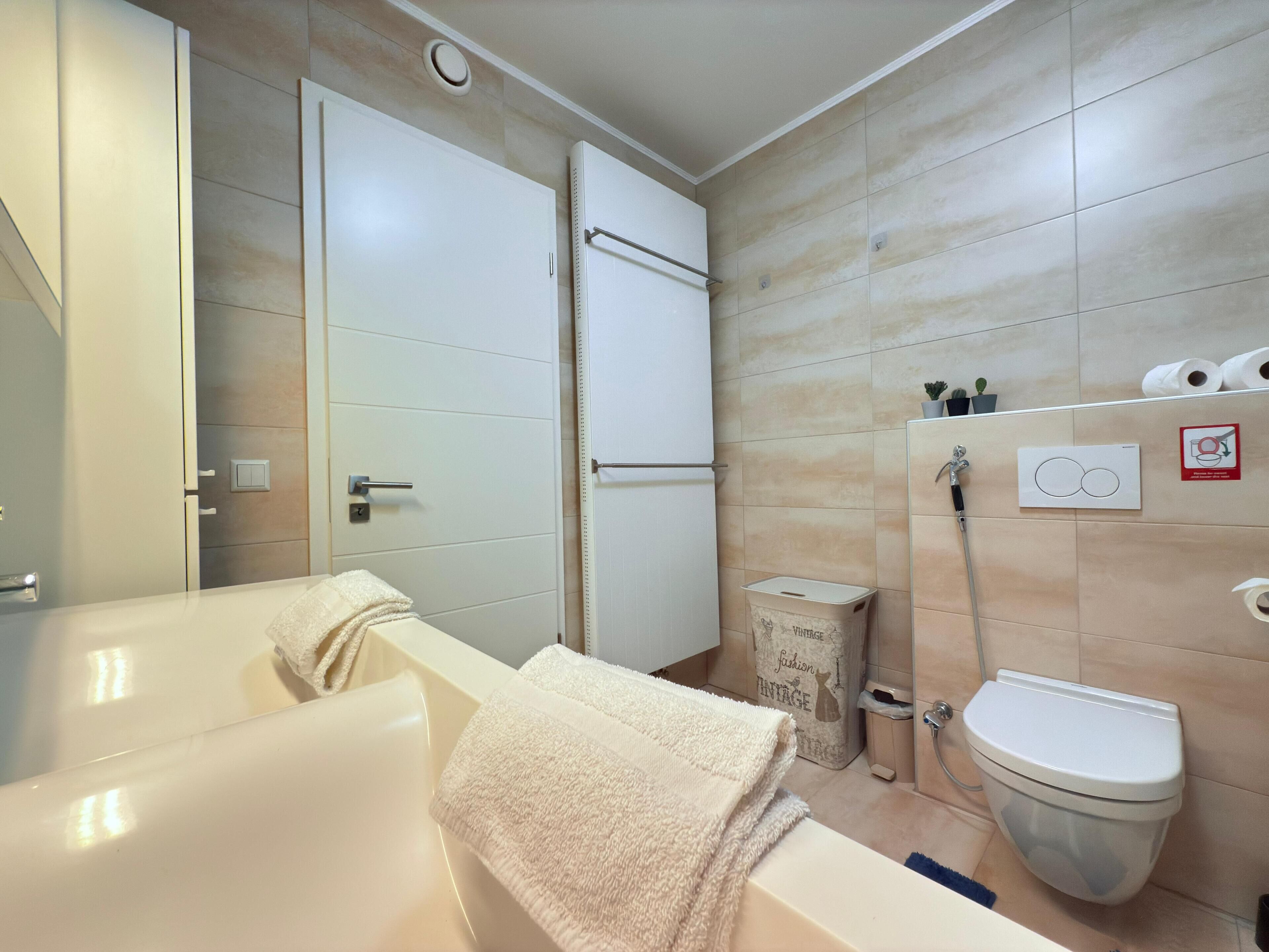 Un baño moderno con bañera, inodoro y zona de ducha.