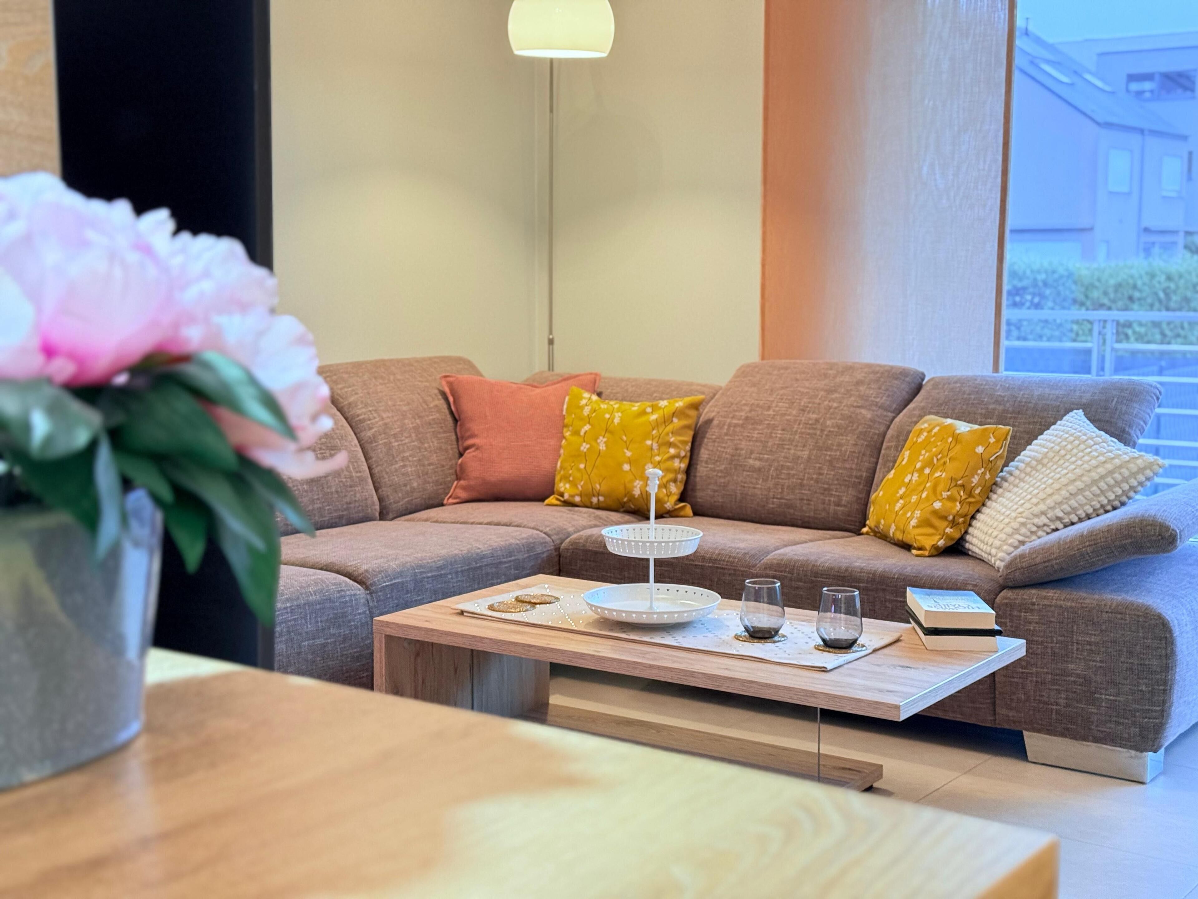 Un salon moderne avec un canapé d’angle marron, une table basse en bois et une plante en pot.