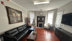 A living room with a black leather sofa, a wooden coffee table, a flat-screen TV, and a fireplace.