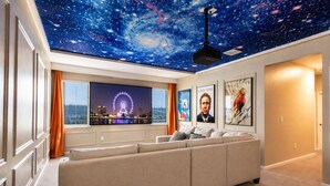 Een thuisbioscoopruimte met een sterrenhemelplafond, een grote flatscreen-tv en ingelijste filmposters.