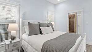A bedroom with a bed, nightstand, lamp, and a door leading to a bathroom.