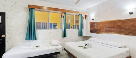 A bedroom with two beds, a ceiling fan, a window with curtains, and a wooden headboard.